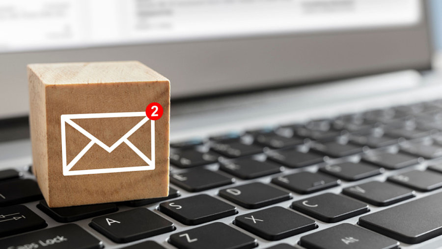 E-Mail-Symbol auf Holzblock mit neuer Meldung auf der Notebook-Tastatur