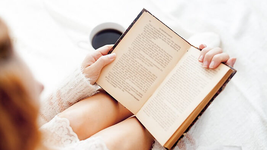 Lady liest Buch und trinkt Kaffee