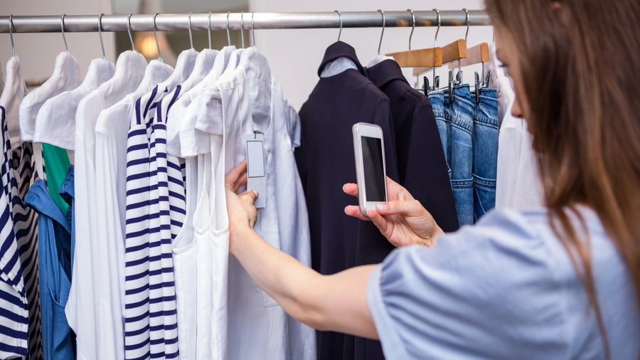 Frau fotografiert Preisschild in Mode-Geschäft