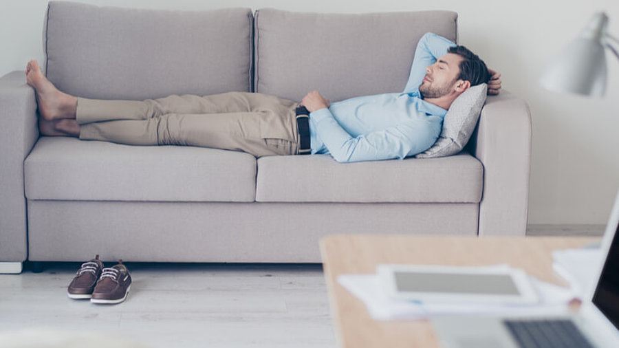 Mann schl&auml;ft auf Couch im B&uuml;ro