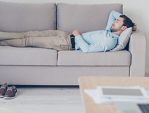 Mann schl&auml;ft auf Couch im B&uuml;ro