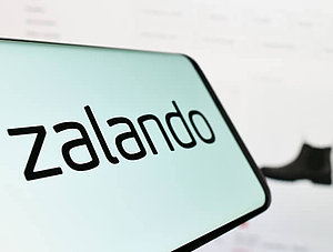 Zalando-Logo auf Smartphone und Webseite im Hintergrund