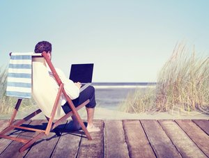 Mann im Liegestuhl arbeitet am Strand