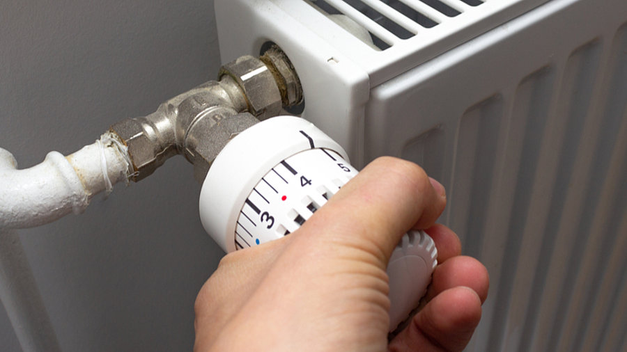 Hand dreht an Heizungsthermostat