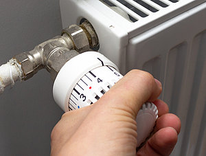 Hand dreht an Heizungsthermostat