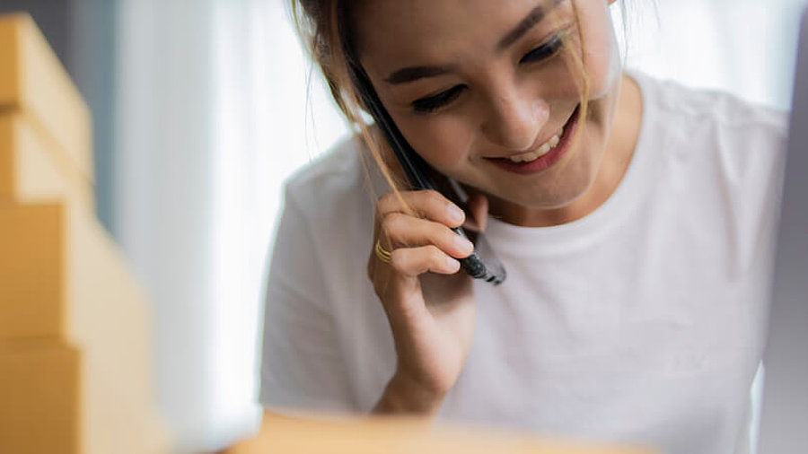 Frau am Telefon mit Paketen