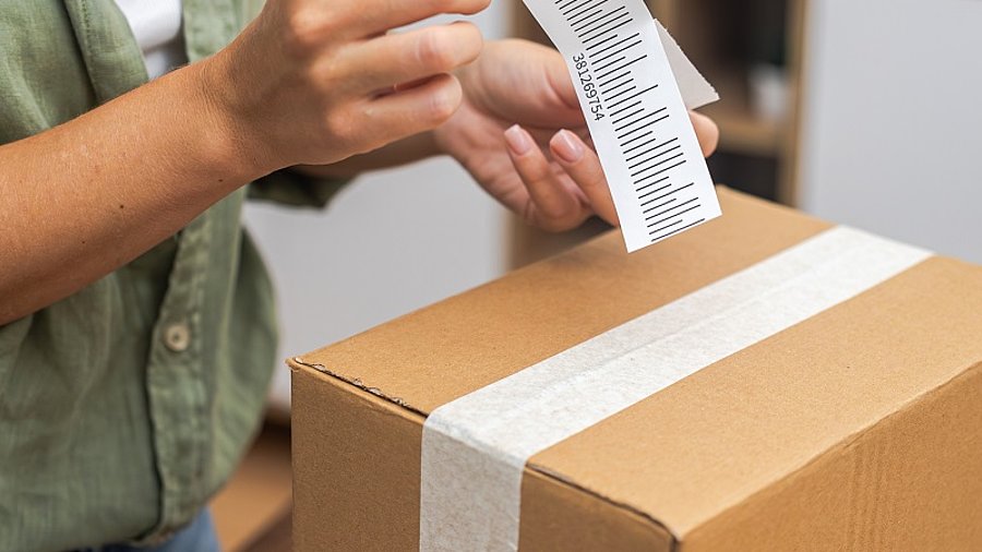 Person klebt Retourenlabel auf Paket