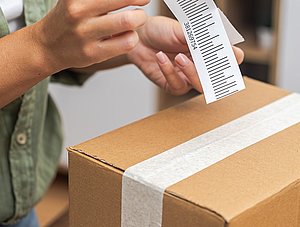 Person klebt Retourenlabel auf Paket