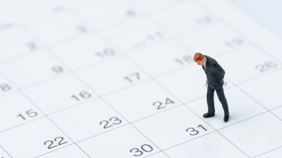 Miniatur von einem Gesch&auml;ftsmann steht auf einem Kalender