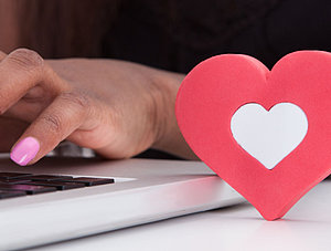 Frau mit rosa Fingern&auml;geln tippt auf Notebook.