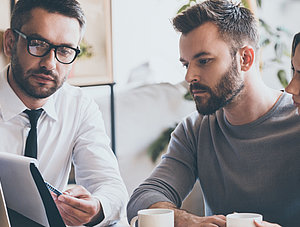 Junges Paar sitzt am Tisch eines Versicherungsvermittlers und l&auml;sst sich etwas erkl&auml;ren