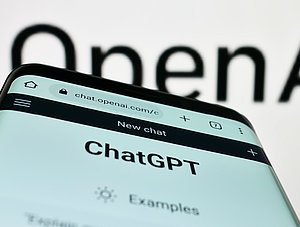 ChatGPT auf Smartphone und OpenAI-Logo im Hintergrund