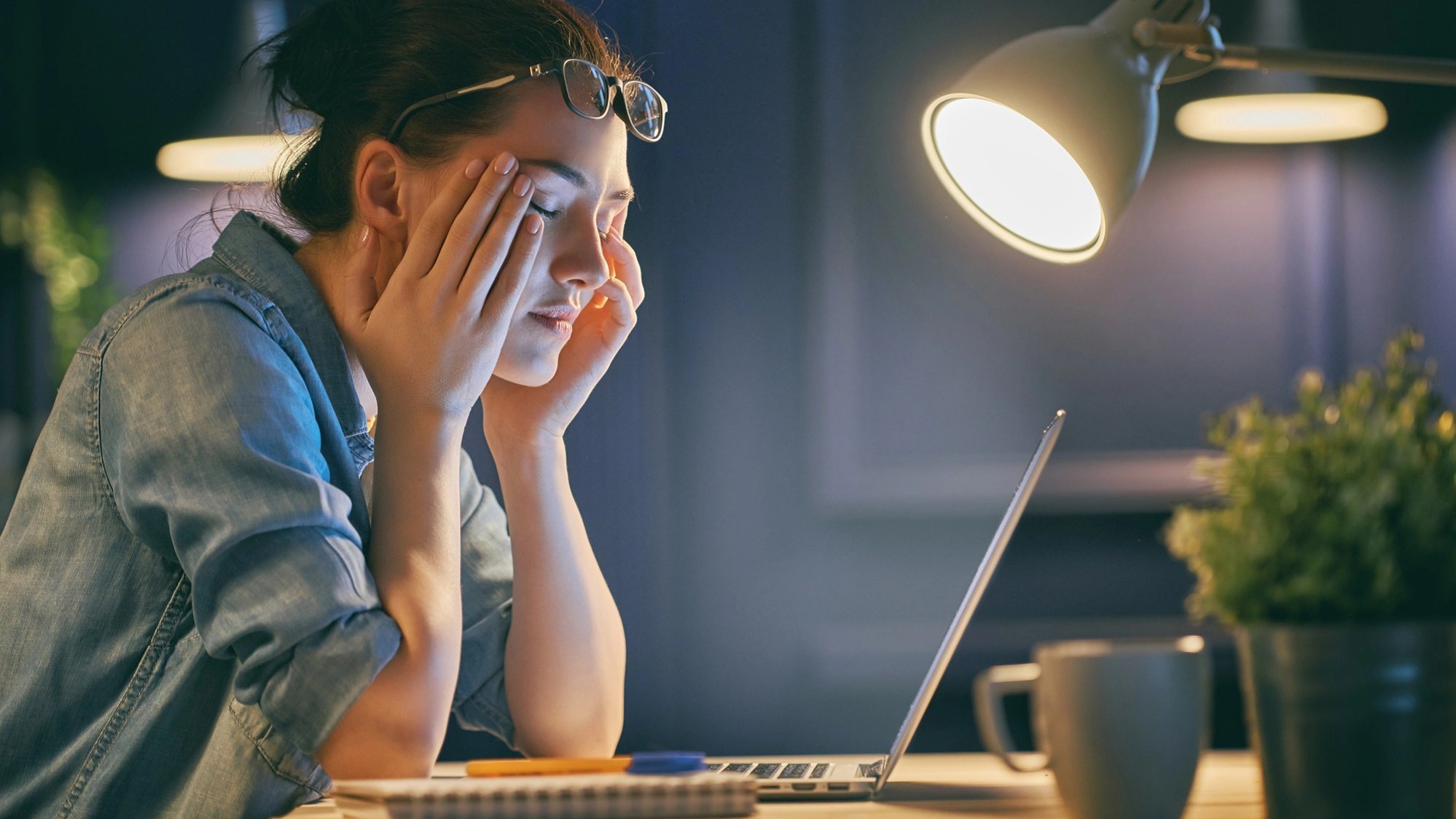 Frau sitzt am Laptop und reibt sich die Augen