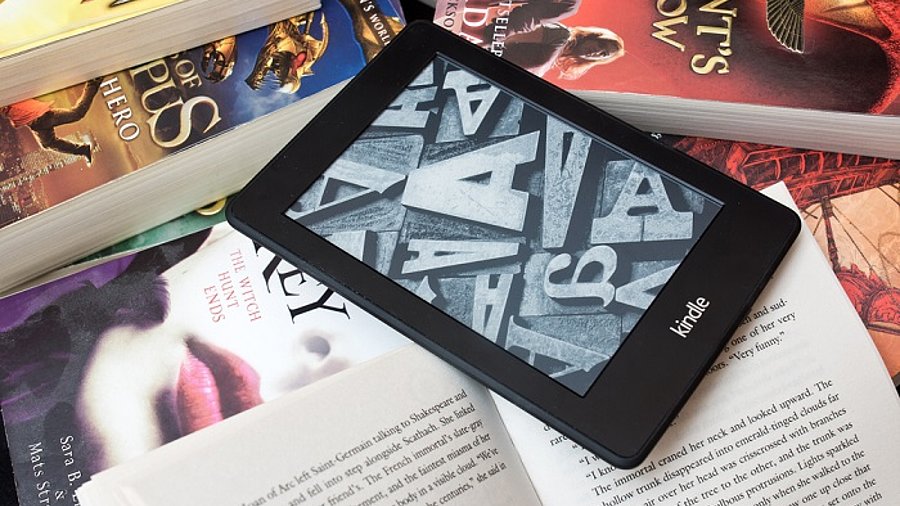 Amazon Kindle E-Book-Reader auf einem Haufen Bücher