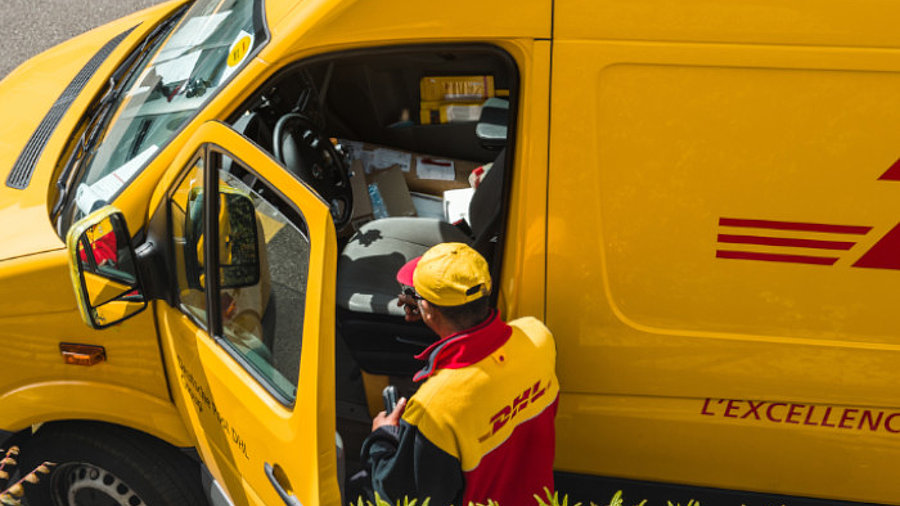 DHL Zusteller mit Wagen