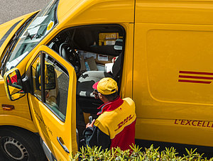 DHL Zusteller mit Wagen