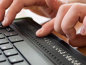 Person verwendet Tastatur mit Brailleschrift