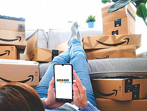 Frau liegt vor Sofa voller Amazon-Kartons