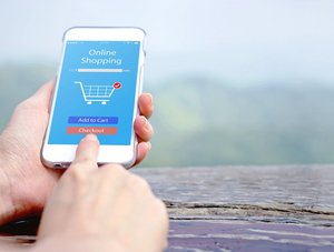 Person shoppt online auf Smartphone, zwei Artikel im Warenkorb, kurz vor Check-out