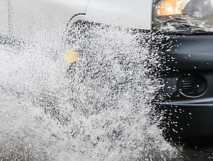 Lieferfahrzeug f&auml;hrt durch &uuml;berschwemmte Stra&szlig;e