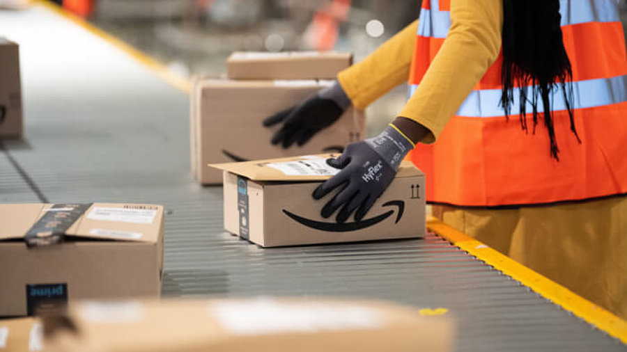 Amazon-Mitarbeiterin am Förderband mit Paketen