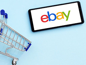 Einkaufwagen und Ebay-Logo auf Smartphone