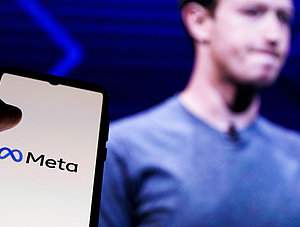 Smartphone mit Meta-Logo neben Mark Zuckerberg