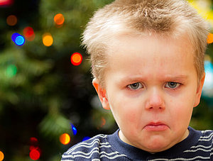 missmutiger Junge vor Weihnachtsbaum