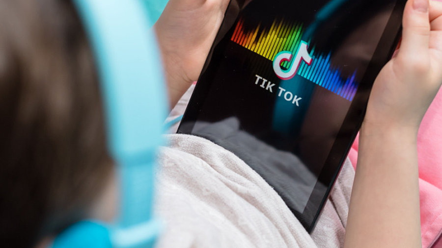 Kind schaut TikTok auf Tablet an