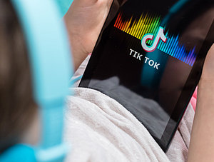 Kind schaut TikTok auf Tablet an