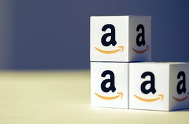 Kleine Pappkartons mit dem Amazon-Logo stehen übereinandergestapelt da