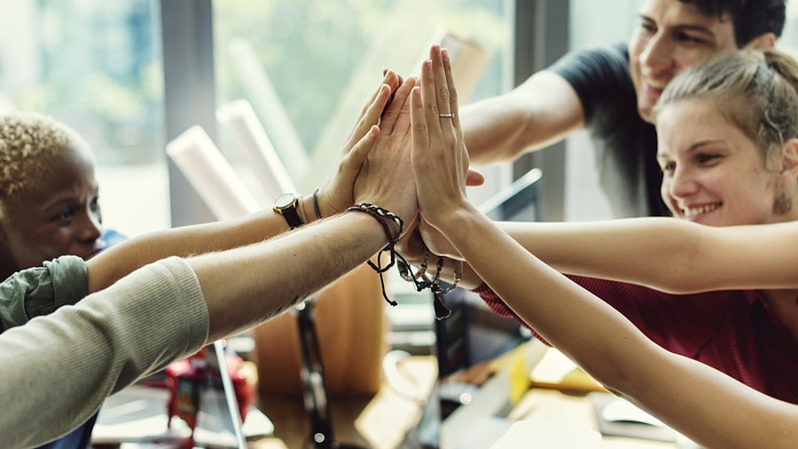 Teamwork: Kolleg:innen machen gemeinsames High-Five