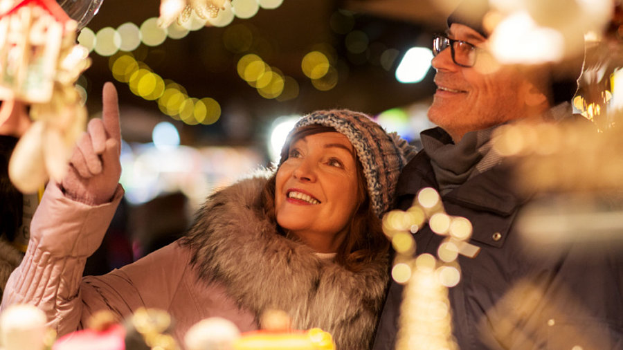 Ehepaar mittleren Alters steht vor Verkaufsstand auf dem Weihnachtsmarkt