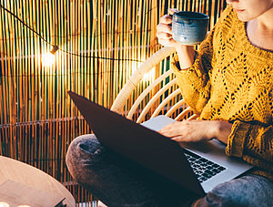 Frau mit Laptop auf Balkon