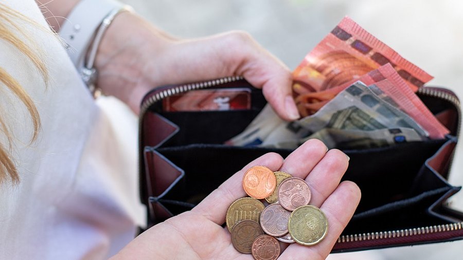 Frau mit wenig Geld und Kleingeld im Portemonnaie