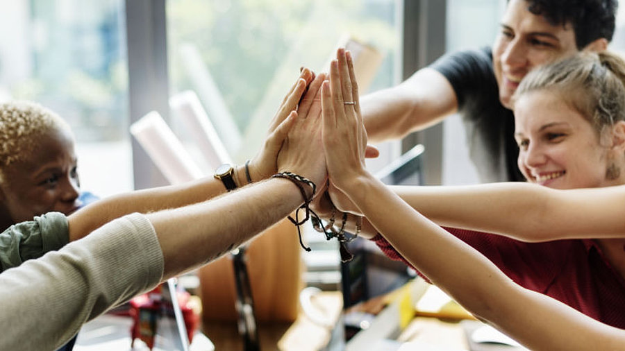 Team im B&uuml;ro macht High Five zusammen