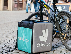 Abgelegter Deliveroo-Rucksack neben einem Fahrrad