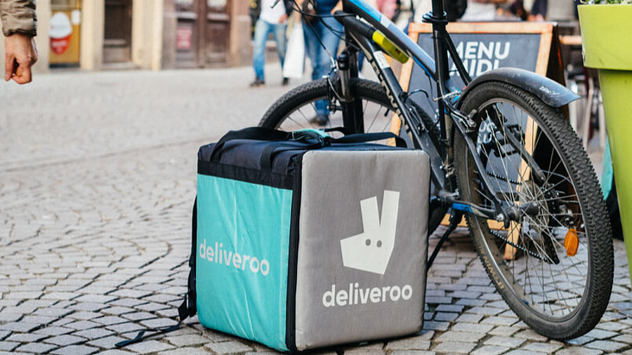 Abgelegter Deliveroo-Rucksack neben einem Fahrrad