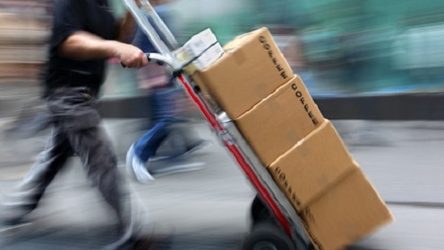 Paketauslieferer mit Sackkarre und Paketen