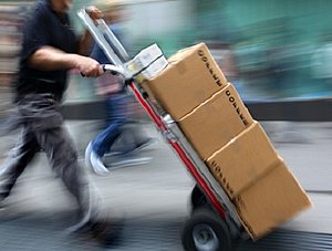 Paketauslieferer mit Sackkarre und Paketen