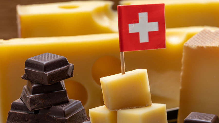 Emmentaler und Schokolade mit kleiner Schweizer Flagge auf Steinplatte