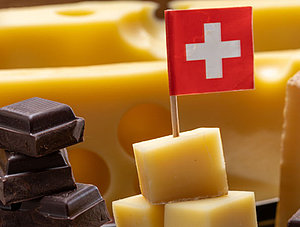 Emmentaler und Schokolade mit kleiner Schweizer Flagge auf Steinplatte