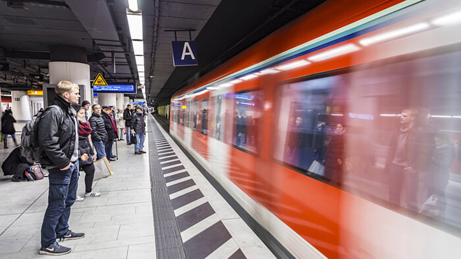 Menschen am Bahngleis warten bei Zugeinfahrt