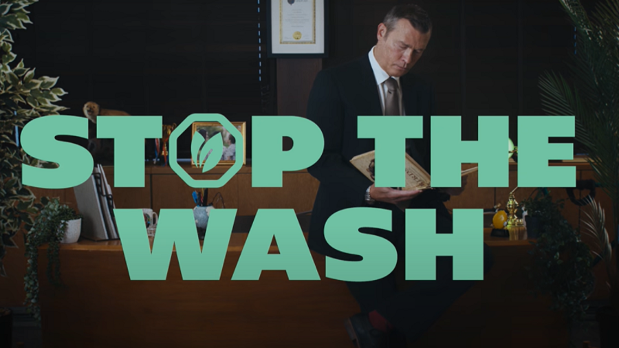 Schriftzug &bdquo;Stop the Wash&ldquo; vor Mann im Anzug hinterm Schreibtisch