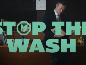 Schriftzug &bdquo;Stop the Wash&ldquo; vor Mann im Anzug hinterm Schreibtisch