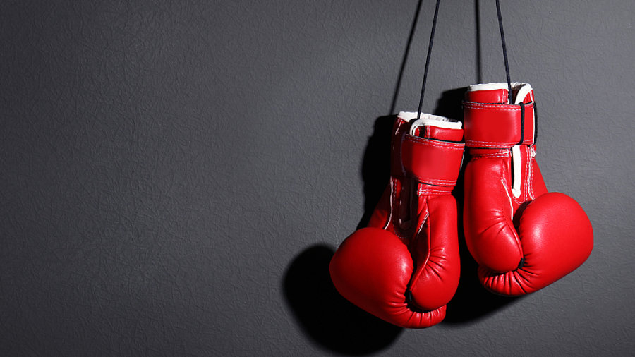 Rote Boxhandschuhe h&auml;ngen an dunkler Wand