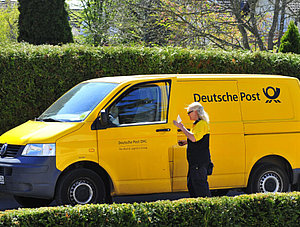 Zustellerin und Lieferfahrzeug der Deutschen Post