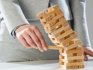 Gesch&auml;ftsfrau, die den Holzblock vom fallenden Turm auf dem Tisch entfernt.