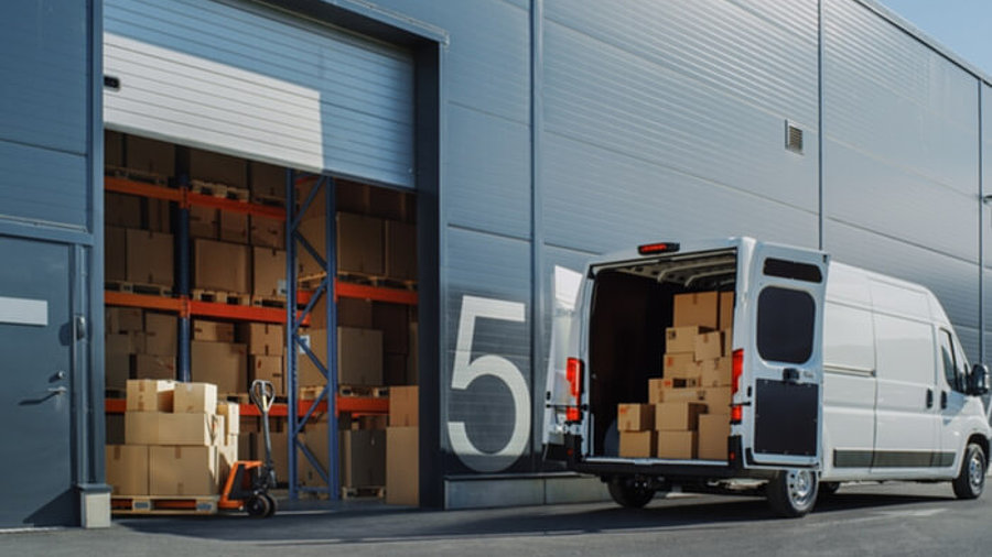 Zustellfahrzeug mit Paketen vor Logistikzentrum