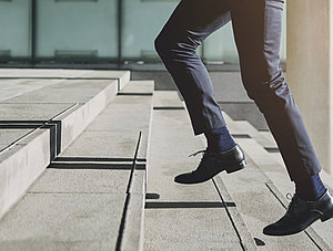 Gesch&auml;ftsmann geht eilig die Treppe hoch um p&uuml;nktlich zur Arbeit zu kommen